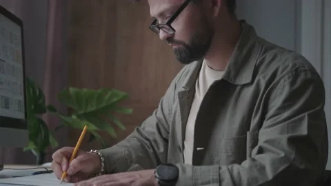 A man works, sits at an office table and writes with a pencil Video stock 137232449
