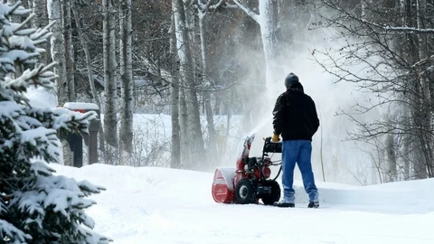 Man works with a snow blower to remove newly fallen snow from driveway. Stock Footage 101617652