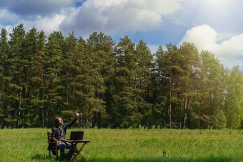 A man works at a table with a laptop in an empty field. Remote work in the field Stock Photos