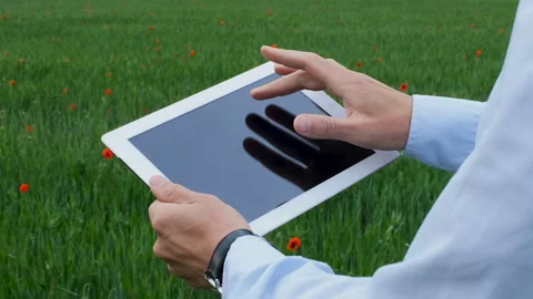 A man works in a tablet against the background of a green field. Stock Footage 134163593