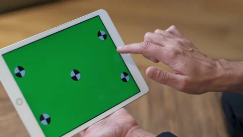A man works at a tablet. A hand in a suit moves along the green screen. Close-up Stock Footage 231895761