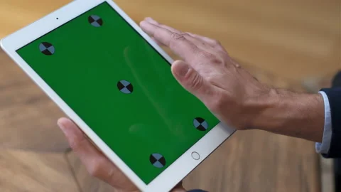 A man works at a tablet. A hand in a suit moves along the green screen. Close-up Stock Footage 232098816