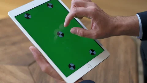 A man works at a tablet. A hand in a suit moves along the green screen. Close-up Stock Footage 234167916