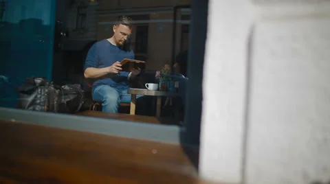 The man works at the tablet sitting in cafeteria Stock Footage 62549631