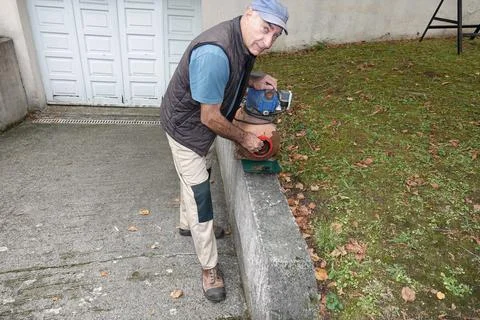 Man works with tools on a device close to a wall outside Stock Photos