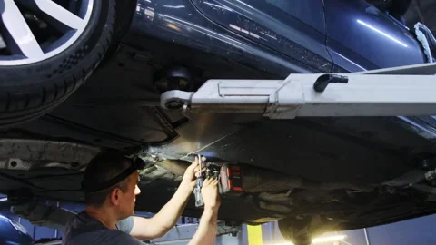 Man works on underside of car using drill to delete breakdown Video stock 317632233