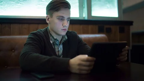 The man works by using a tablet in a cafe Stock Footage 71352203