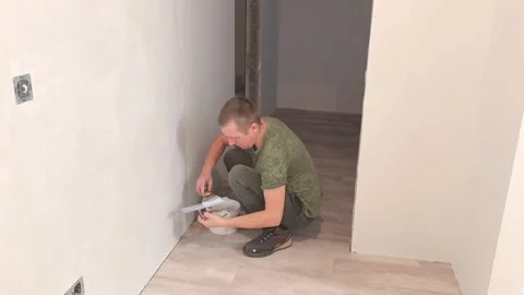 Man works on wall to install electrical outlet in new apartment renovation Stock Footage 326698354