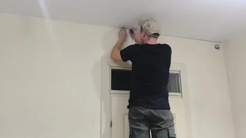 Man works on wall while installing cable in a room at night in a quiet area Stock Footage 329408906