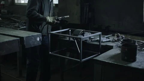 The man works with a welding machine in the workshop and welds on a metal Stock Footage 135747238