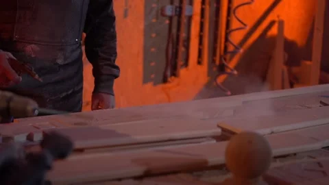 A man in a workshop blows off sawdust from a workpiece after processing Stock Footage 120600096