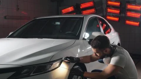 Man in the workshop checks the quality of car paint using a flashlight Stock Photos