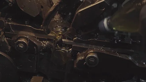 A man in the workshop helps an automatic machine by pouring oil on it. The Stock Footage 116077181