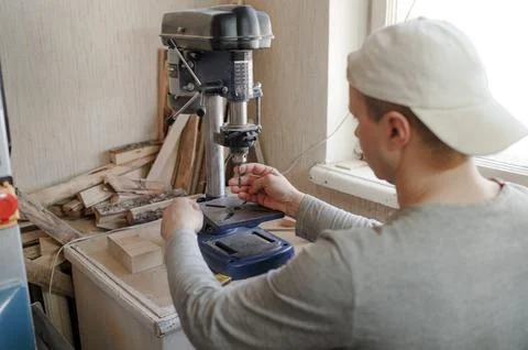 A man in the workshop inserts a drill bit into a drilling machine Stock Photos