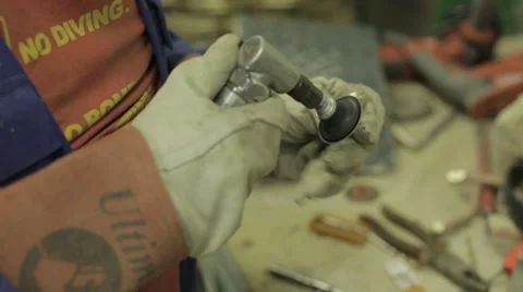 Man in a workshop polishing a small metal ball to be attached to a bronze statue Stock Footage 58640724
