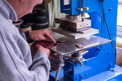 The man in the workshop presses the lever on the press machine to get the emb Stock Photos