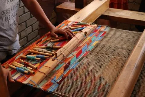 Man in a workshop standing next to a traditional loom, about to weave a color Foto stock