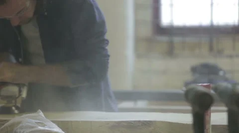 Man in workshop using a sander on  a piece of oak wood Stock Footage 58930429
