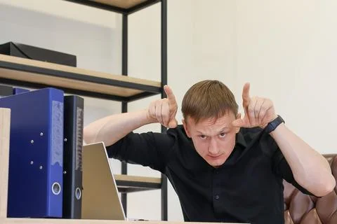 Man at workstation mimicking devil horns with hands Stock Photos