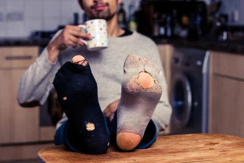 Man with worn out socks having coffee in kitchen 스톡 사진