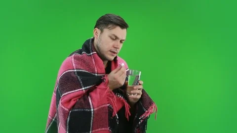 A man wrapped in a blanket drinks a pill and drinks it with water. Stock Footage 127241215
