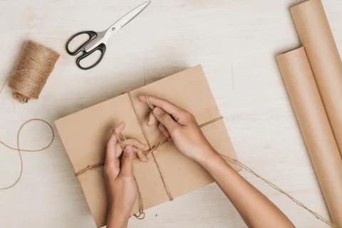 Man wrapping gift. A parcel wrapped in brown paper and tied with rough twine Foto stock