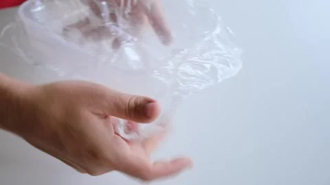 A man wraps an empty plastic container with cling film. Packing of dishes. The Stock Footage 323708352