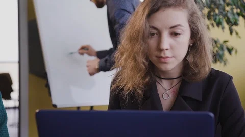 Man write on flipchart, female watch on laptop screen, sitting at desk in room. Stock Footage 115638268