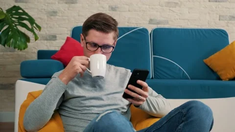 Man write a message using a mobile phone and drinking a cup of tea. Stock Footage 146038097