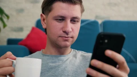 Man write a message using a mobile phone while is drinking a cup of tea. Stock Footage 146238172