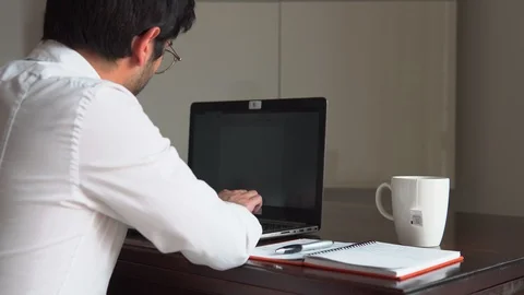 Man writes on the computer and drinks his hot cup while working at his house Stock Footage 129441813