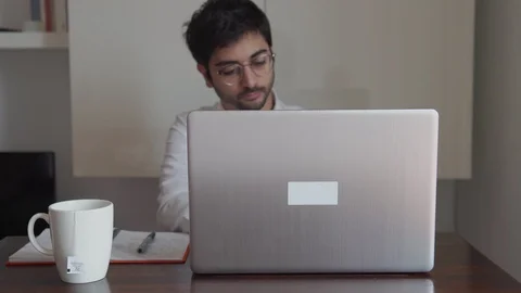 Man writes on computer and stops to think with pen Stock Footage 129441079