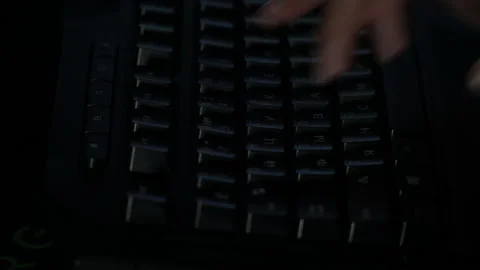 A man writes in a dark room on a keyboard with English and Russian fonts Stock Footage 237375232