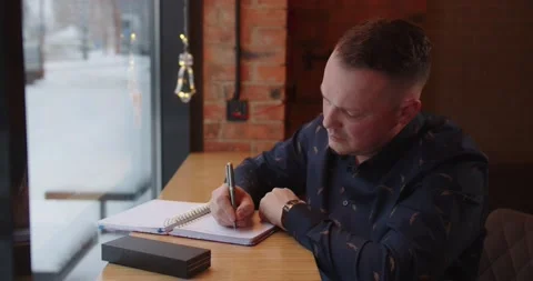 The man writes down in a notebook plans for the future. Man writes text notebook Stock Footage 168249318