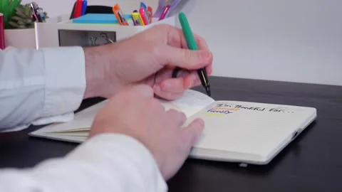 Man Writes Gratitude Lists in Journal with Markers Stock Footage 325447313