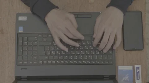 Man writes by laptop keyboard next to him a pack of cigarettes and a lighter Stock Footage 130089739