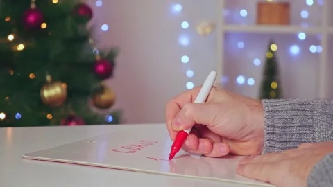 A man writes marker board table with Christmas decor goals plans new year Stock Footage 220451663
