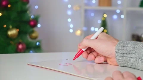 A man writes marker board table with Christmas decor goals plans new year Stock Footage 221601926