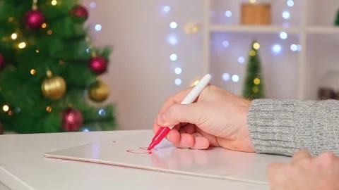 A man writes marker board table with Christmas decor goals plans new year Stock Footage 222432265