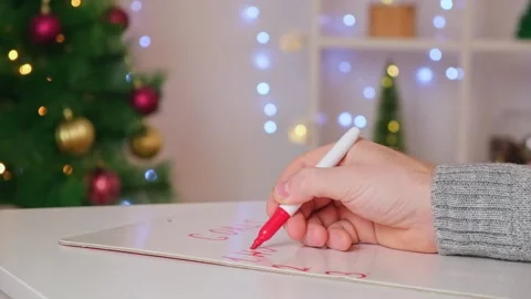 A man writes marker board table with Christmas decor goals plans new year Stock Footage 223229330