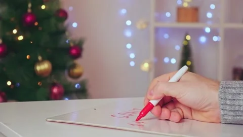 A man writes marker board table with Christmas decor goals plans new year Stock Footage 224757254