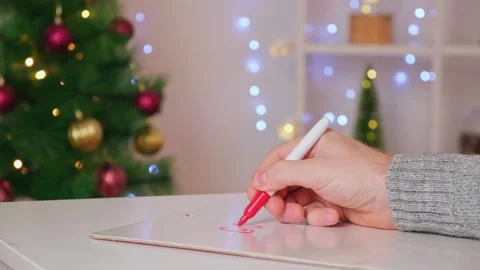 A man writes marker board table with Christmas decor goals plans new year Stock Footage 225537518