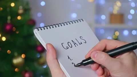 Man writes marker board at white table with Christmas decor goals and plans new Video stock 220451670