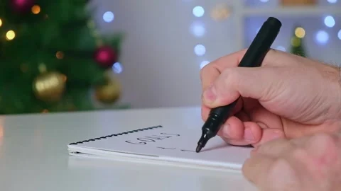 Man writes marker board at white table with Christmas decor goals and plans new Stock Footage 221867892