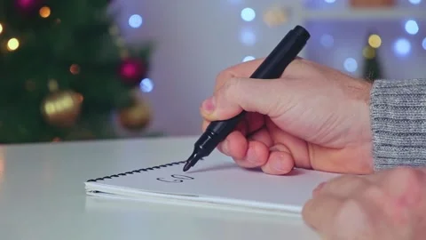 Man writes marker board at white table with Christmas decor goals and plans new Stock Footage 223940947