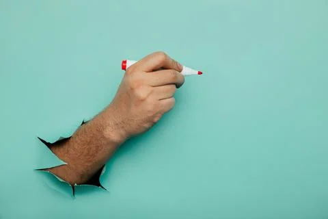A man writes a marker on a broken blue paper wall Stock Photos