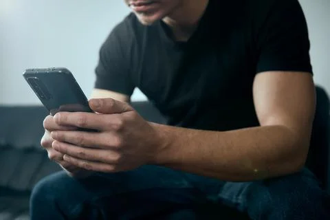 Man Writes a message on the phone. Scrolls through the feed on the phone Stock Photos