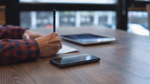 The man writes in a notebook and works on a tablet Stock Footage 86490978