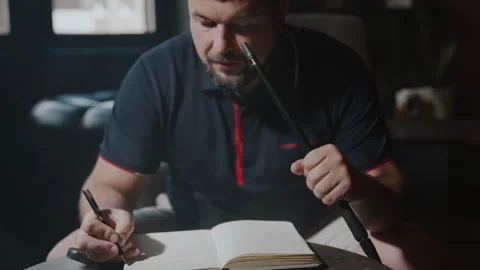 A man writes notes in a book while smoking a hookah. A man with a mustache, a Stock Footage 253491776