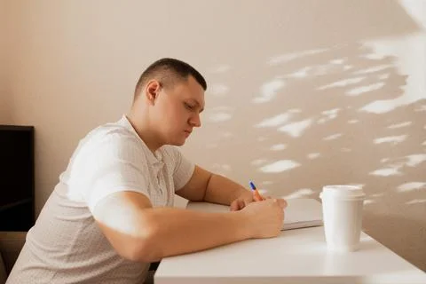 The man writes notes in the diary. A man writes notes at home. Stock Photos